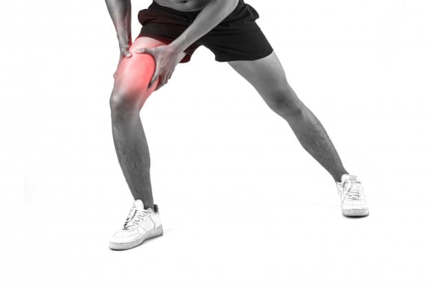 Young sport man with strong athletic legs holding knee with his hands in pain after suffering ligament injury isolated on white.