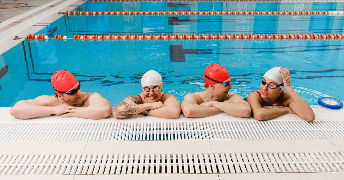 four friends sitting along the pool 