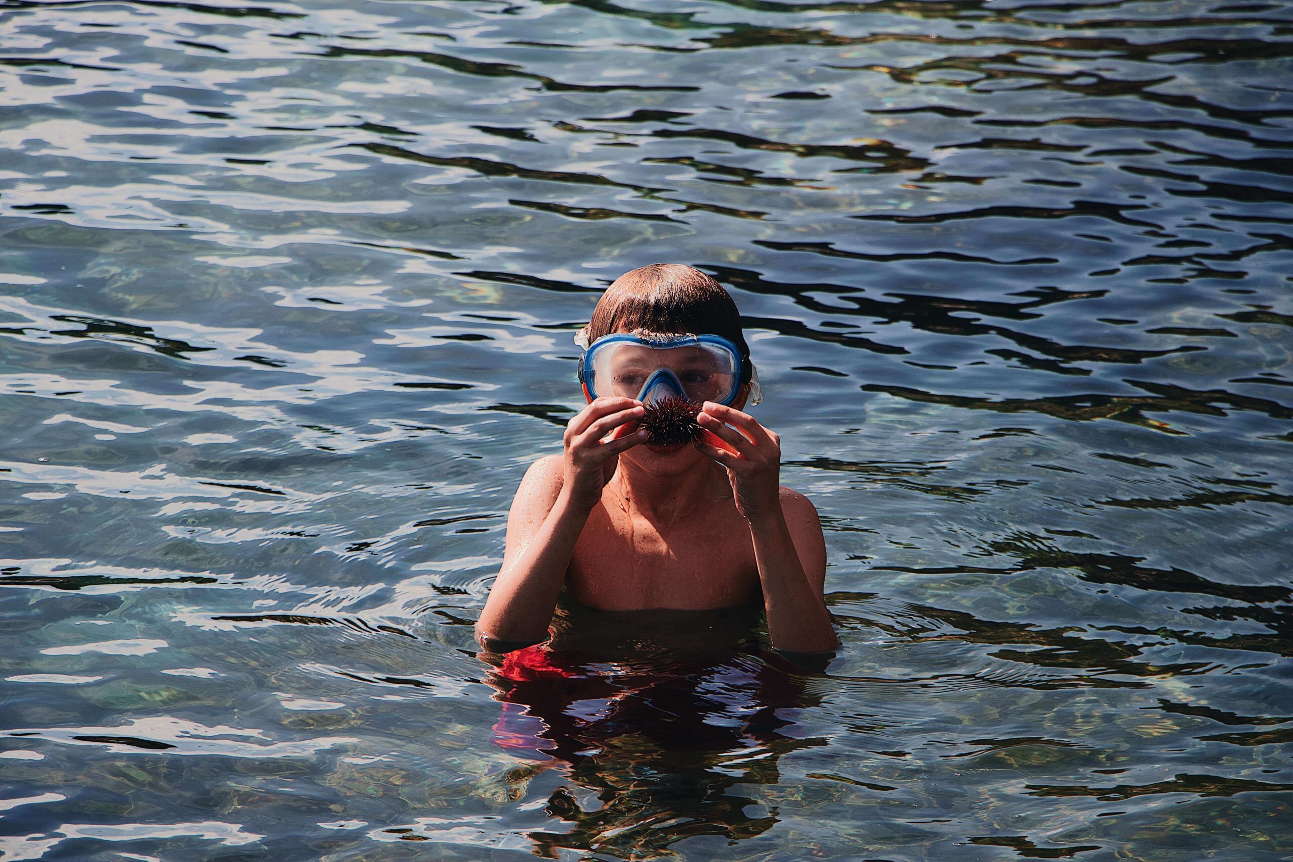 Kid is wearing eye goggles during his swimming lessons